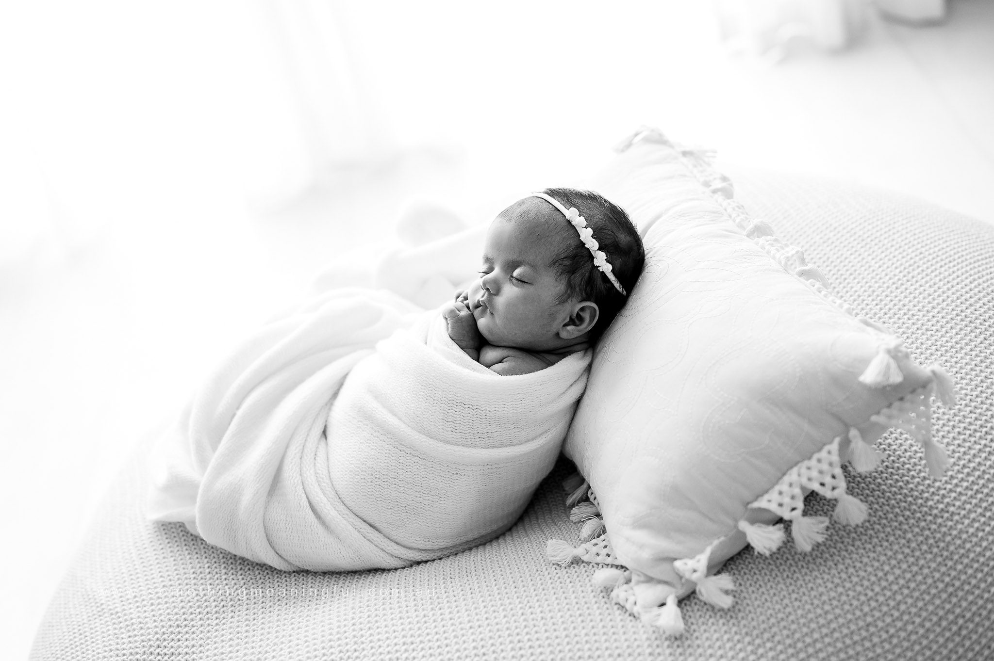 photo of a newborn baby in black and white swaddled in soft fabric in photography studio