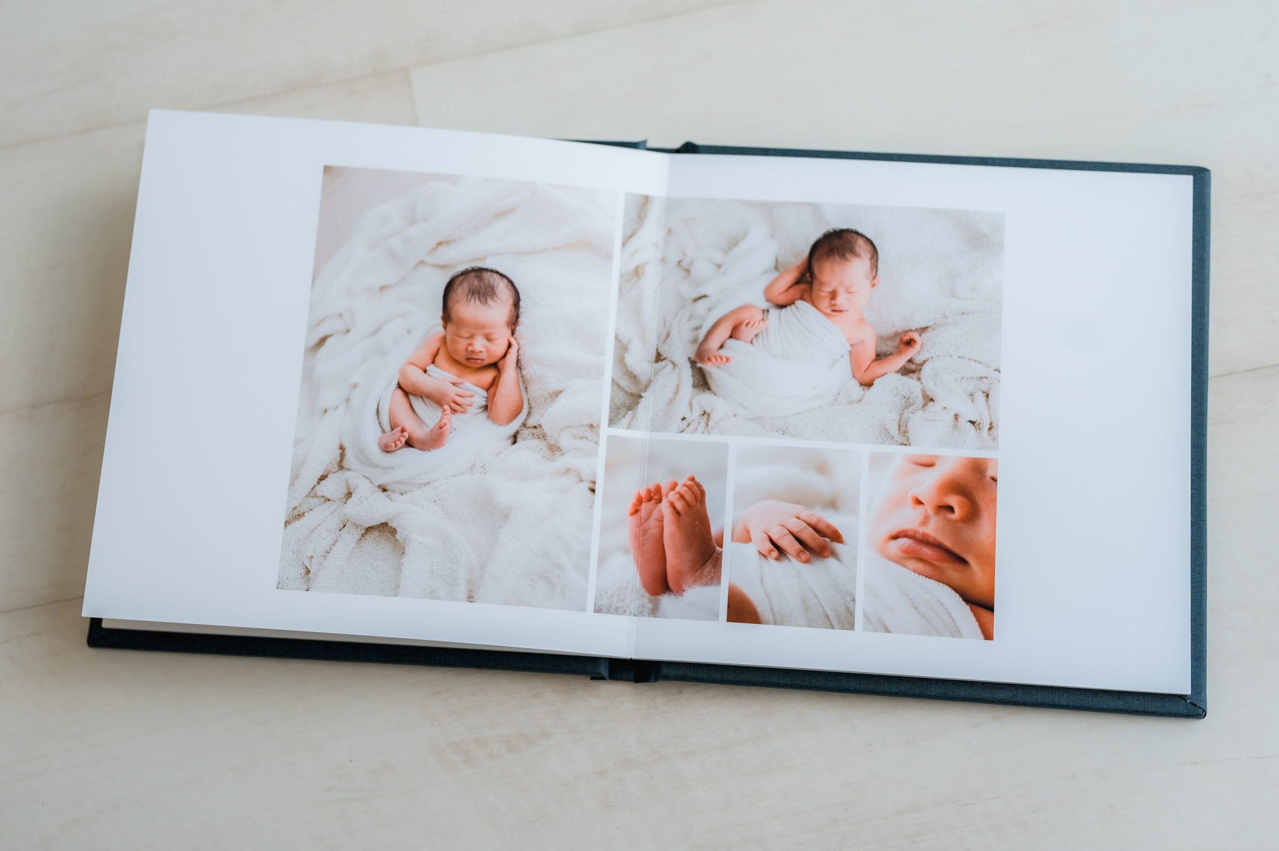 An heirloom album displays several pictures of a newborn baby wrapped in a white blanket, lying on a soft white surface, with close-up shots of the baby's feet and face—perfect for newborn photography Melbourne.